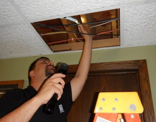 Home inspector inspecting above a ceiling panel